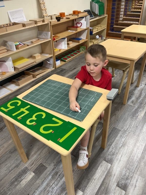 Amici preschooler tracing numbers on a counting board